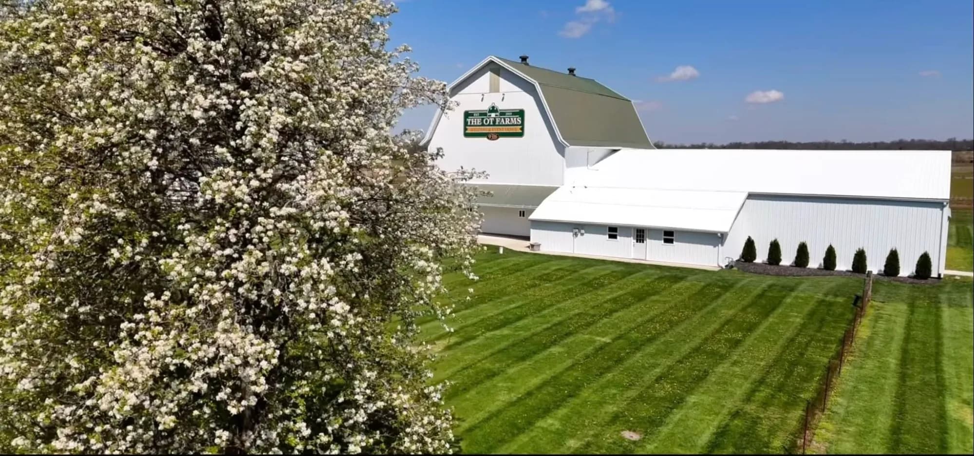 The OT Farms white barn with green roof and gravel path leading to the entrance