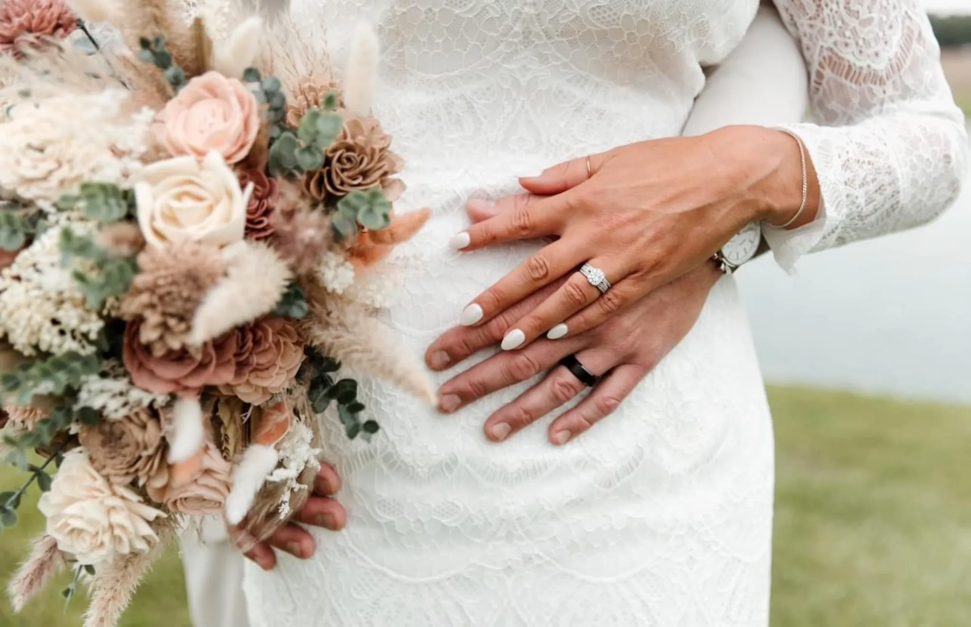 Close detail of a couple's hands with wedding rings and a romantic bouquet