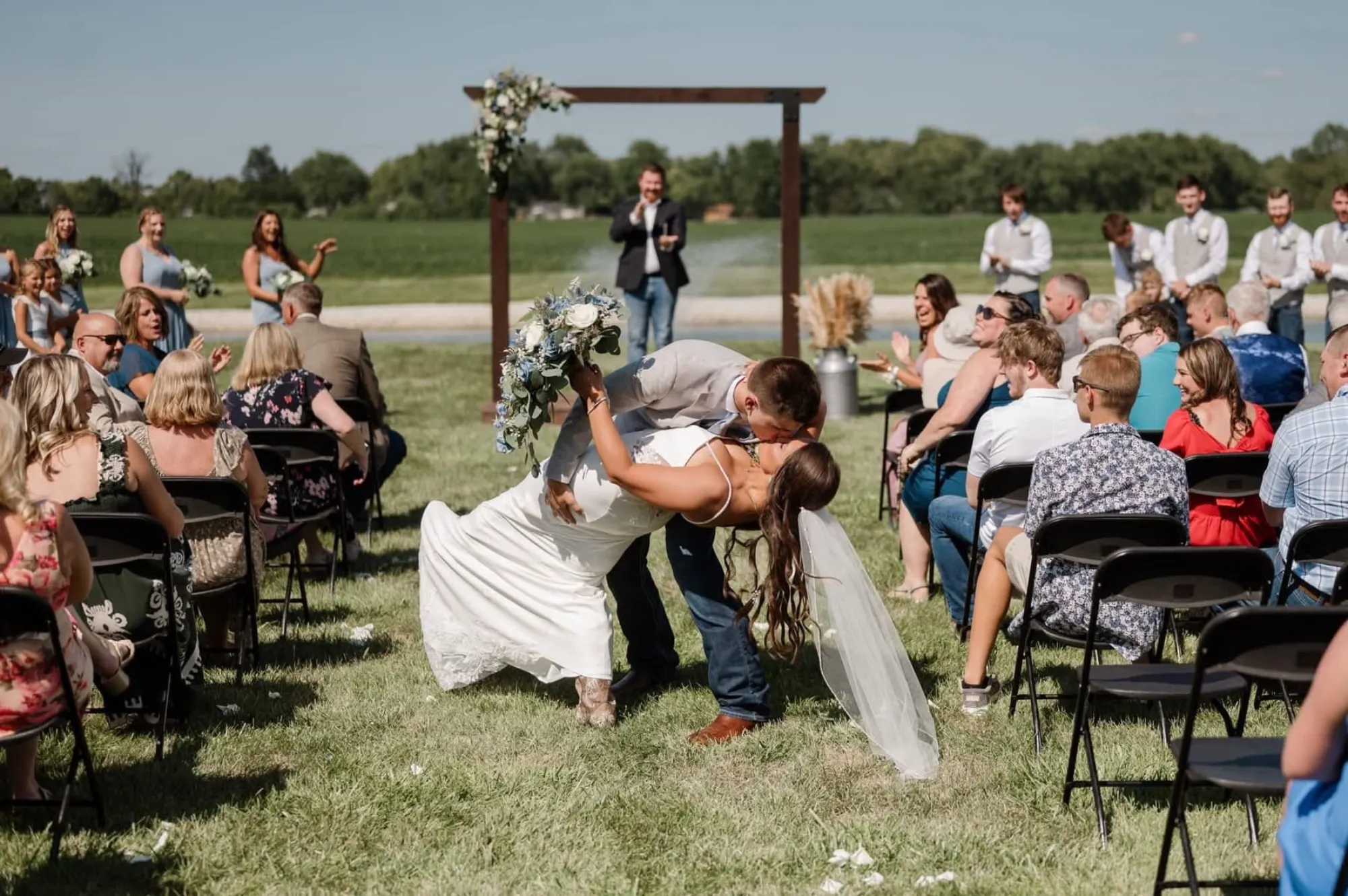 Floral ceremony arch with pampas grass overlooking a pond and open fields